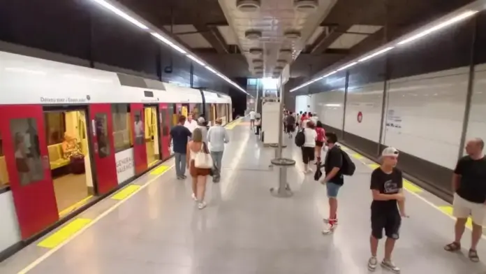 Viagers de Metrovalencia dins o a l’estació amb cartells del servei