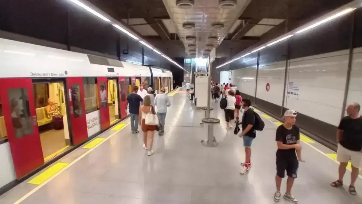Viagers de Metrovalencia dins o a l’estació amb cartells del servei