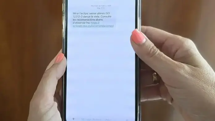 Persona observant un mòbil amb un SMS, en relació amb l’eclips solar a la Comunitat Valenciana