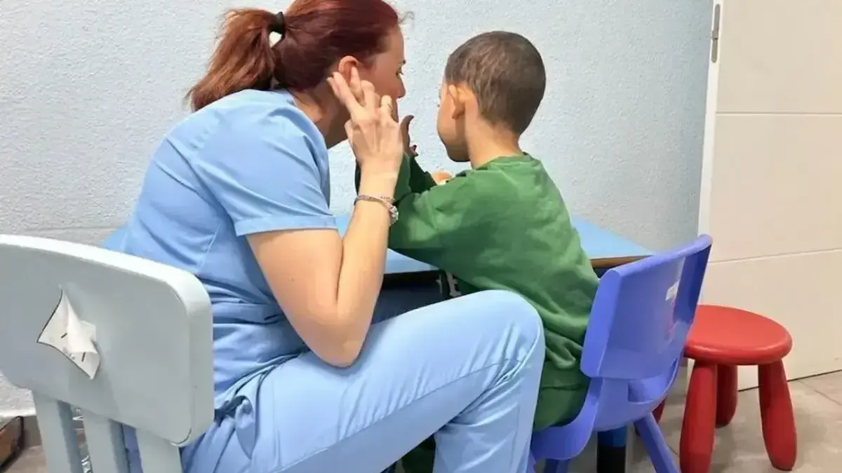 Treballador/a d’atenció social ajuda una persona dependent en un entorn assistencial.